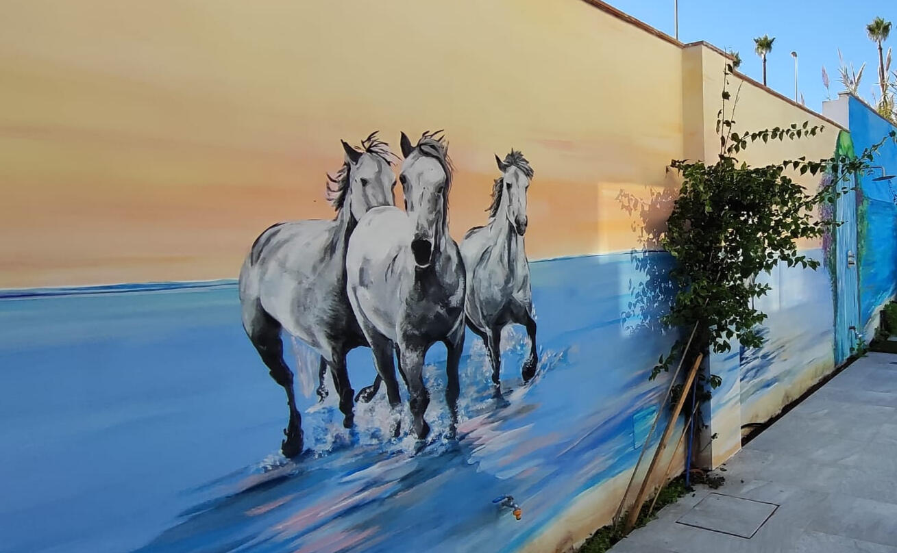Mural en pared exterior de caballos sobre el mar. Pintura realizada por encargo en Tooker Vacation Properties en la Cala de Mijas